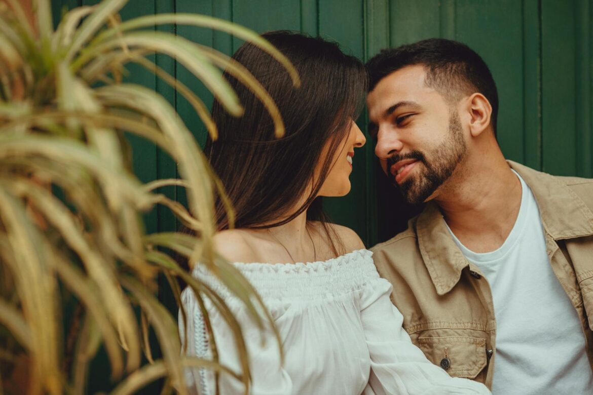 Charming couple sharing a romantic moment outdoors with vibrant greenery.