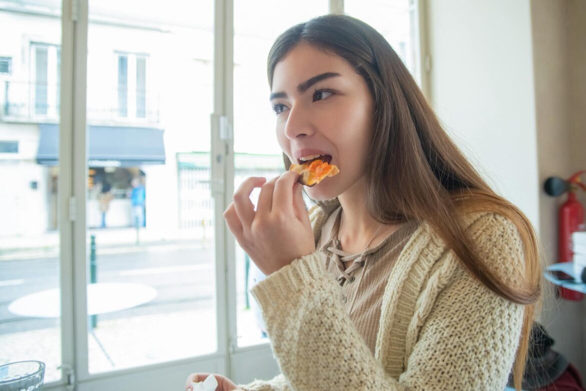 A young woman savoring a slice of pizza indoors in Portugal. Casual dining experience.